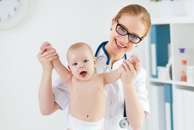 Eine Ärztin mit einem lachenden Baby.