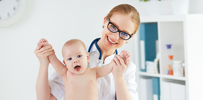 Eine Ärztin mit einem lachenden Baby.