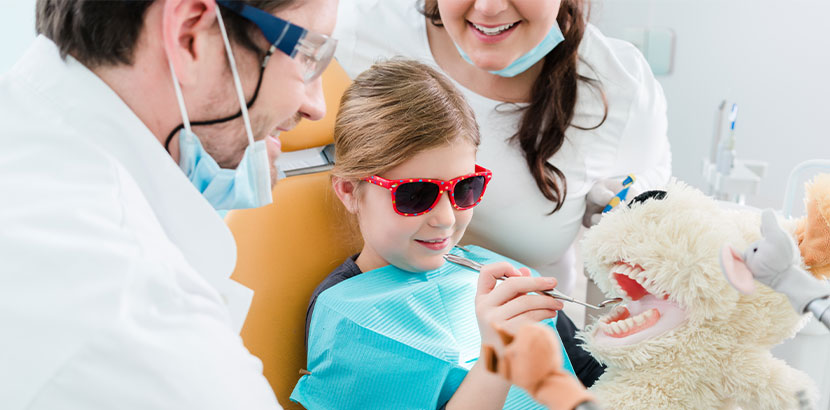 Ein Mädchen in der Zahnarztpraxis, das ein Werkzeug in die Hand nehmen darf.