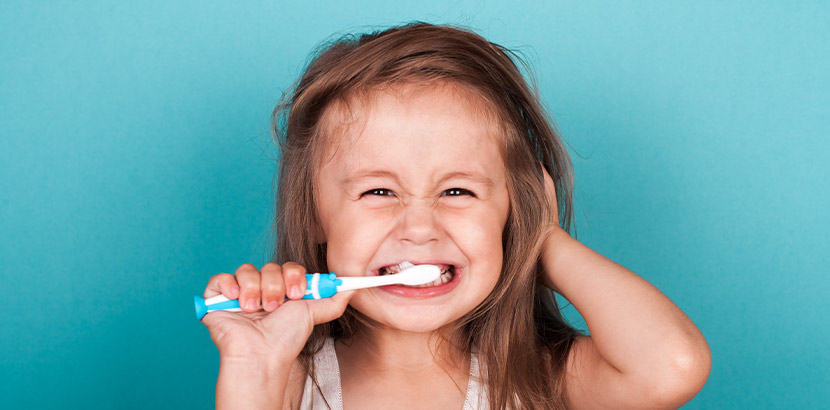 Ein junges Mädchen mit einer Kinderzahnbürste beim Zähne putzen.
