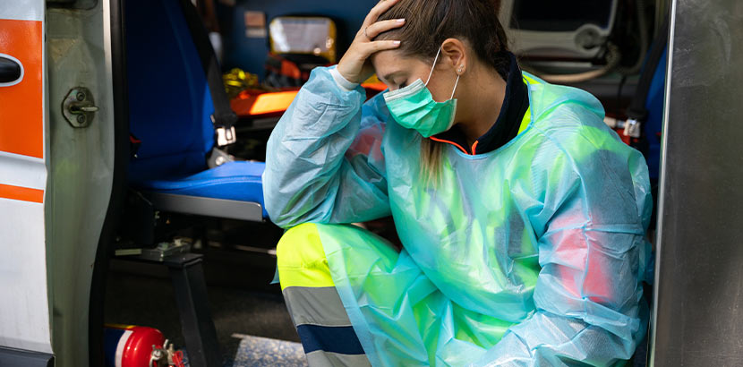 Sanitäterin in Krankenwagen ist mit ihren Kräften am Ende und legt ihre Hand auf ihr Gehirn.