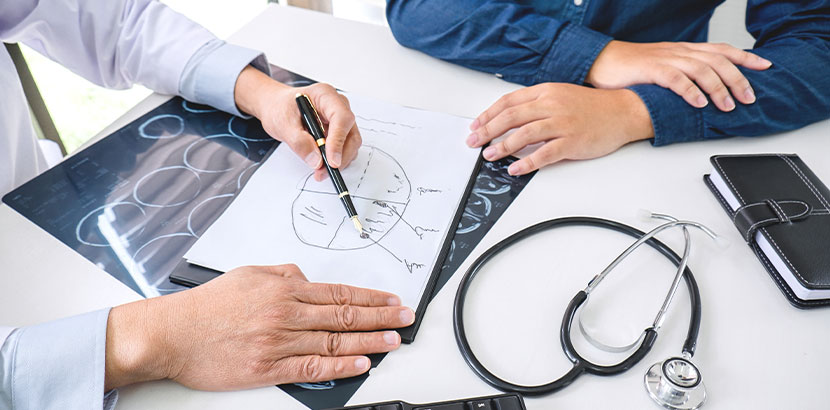 Arzt erklärt Patient Daten einer CT Untersuchung im Behandlungsraum neurologischer Praxis.