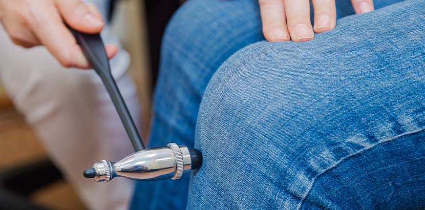 Neurologin verwendet Reflexhammer für klinische Kontrolle am Knie.