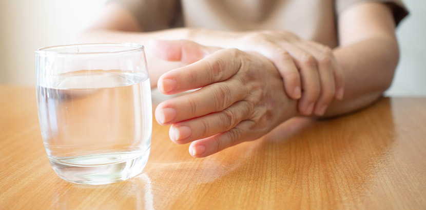 Patient versucht nach Schlaganfall ein Glas zu heben.