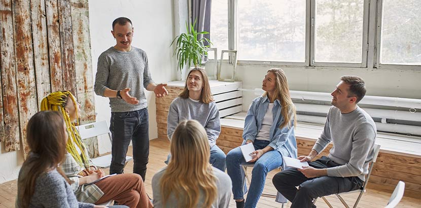 Mehrere Personen in Gruppentherapie besprechen relevantes Thema.