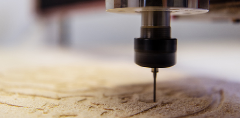 Eine CNC-Fräse die filigrane Details in ein Holzstöck fräst.