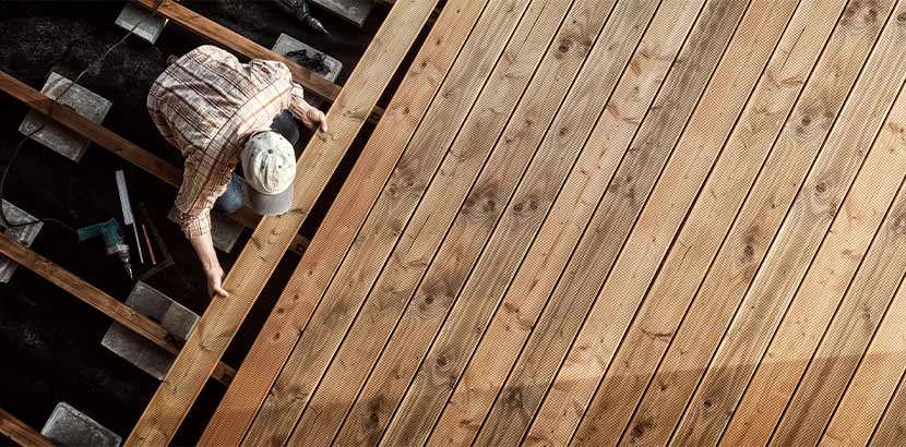 Meistertischler beim Verlegen von Holzbrettern als Bodenbelag für eine Holzterrasse.