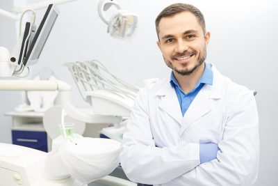 Freundlicher Arzt in heller, moderner Zahnarztpraxis.