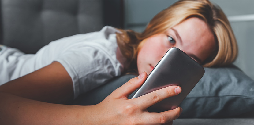 Teenager mit Kummer blickt auf ihr Smartphone.