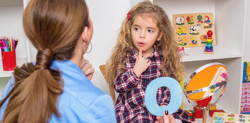 Junges Mädchen in einer Einheit logopädischer Therapie zur Förderung der Sprachentwicklung.