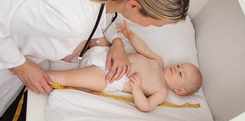 Ärztin verwendet Maßband um zu messen, wie groß ein Baby ist.