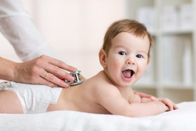 Baby lächelt und fühlt sich wohl bei Arzttermin.