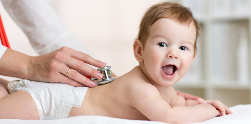 Baby lächelt und fühlt sich wohl bei Arzttermin.