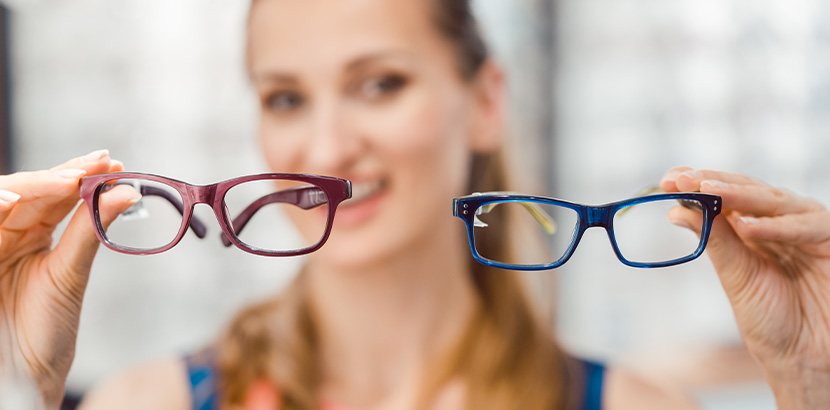 Junge Frau hält zwei Brillen in unterschiedlichen Farben.