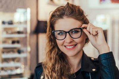 Junge Frau probiert neue Brille bei Optikermeister an.