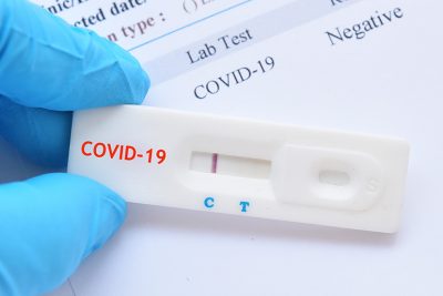 Arzt mit COVID-19 Testkassette nach Schnelltest durch Nasenabstrich.