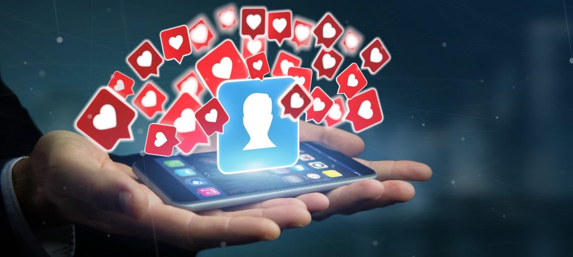 Hände, die ein Tablet halten, aus dem ein von Herzchen umgebener Avatar aufsteigt,. Wie wichtig ist Social Media wirklich?