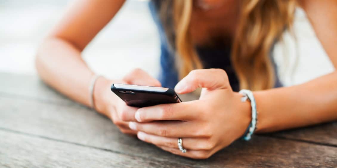 Junges Mädchen, das mit ihrem Smartphone beschäftigt ist. Wie wichtig ist Social Media für den Unternehmenserfolg?