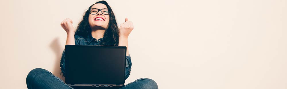 June Frau vor hellem Hintergrund mit Laptop auf dem Schoß, die sich darüber freut, dass Google ihre Webseite endlich findet.