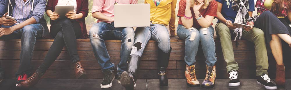 Gruppe von jungen Menschen, die mit Laptop und Smartphone im Internet surfen.