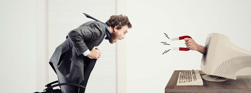 Junger Mann, der von einem Magneten durch den Computer Bildschirm gesaugt wird. Inbound Marketing.