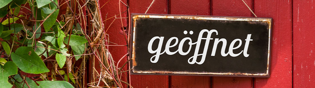 Schild, auf dem "geöffnet" steht, und das einer rot gestrichenen Ladentür hängt. Lokal besser gefunden werden.