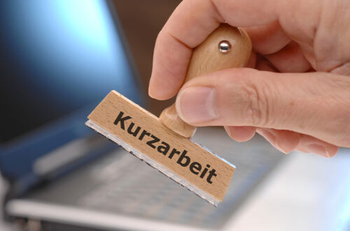 Holzstempel auf dem das Wort Kurzarbeit zu lesen ist. Infos über Corona Kurzarbeit.