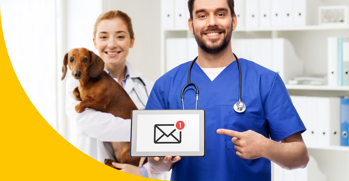 Tierarzt zeigt Tablet mit Symbol dafür das "Newsletter landet im Spam" nicht mehr sein Problem ist. Im Hintergrund befindet sich eine Arzthelferin mit Dackel im Arm.