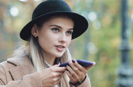 junge Frau mit Hut führt eine Google Voice Search durch