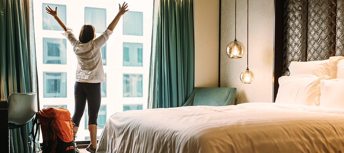Frau in Hotel, Arme freudig in die Luft gehoben