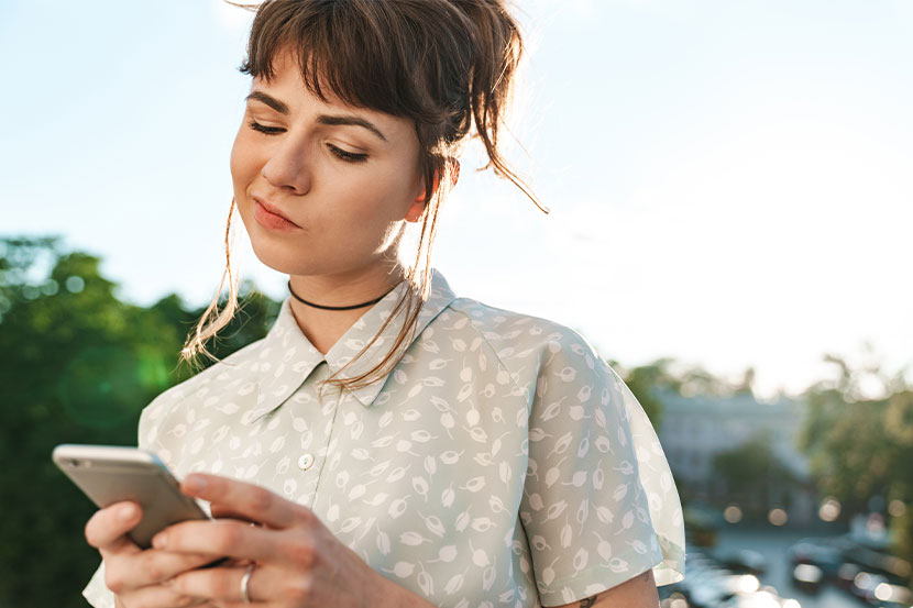 Junge Frau schreibt Google Rezension auf ihrem Smartphone um eine Unternehmen zu bewerten